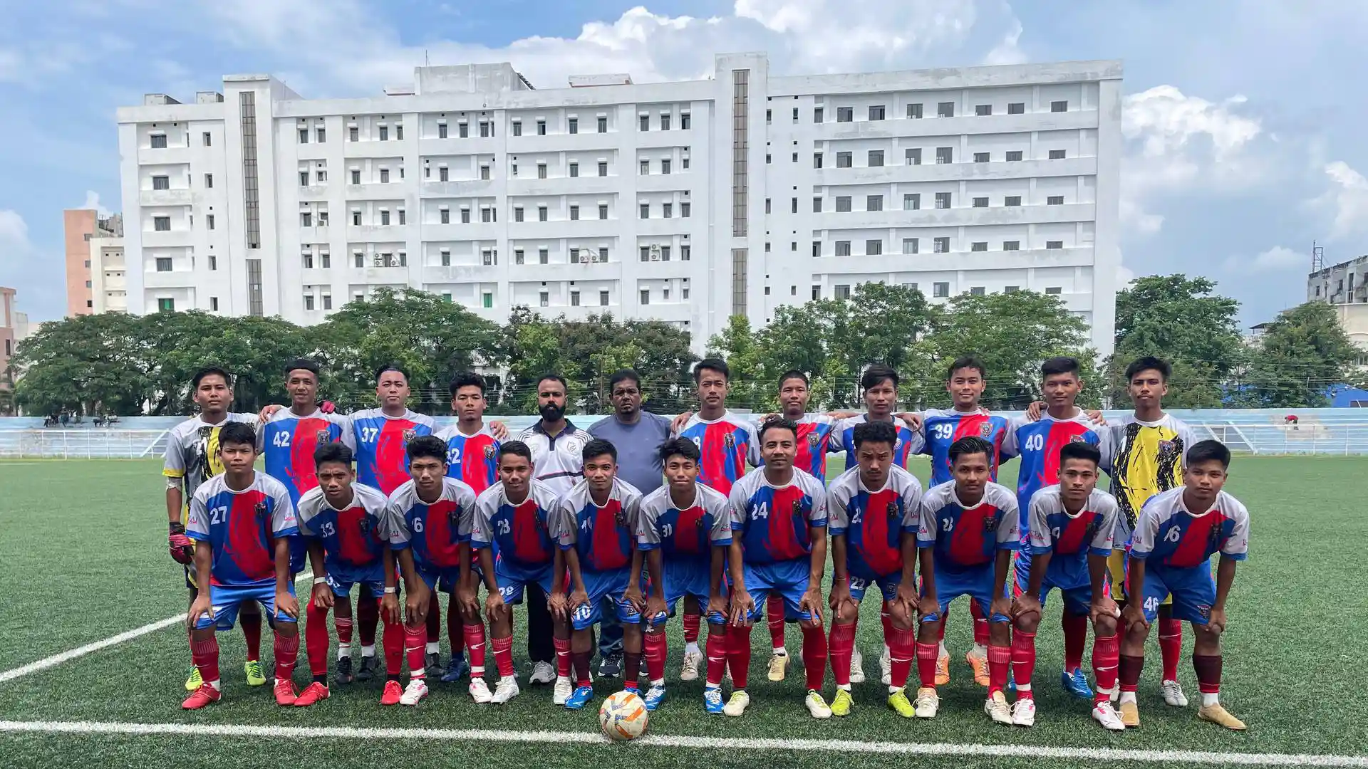 The ICFAI FC squad and staff lined up on the pitch in front of the University building